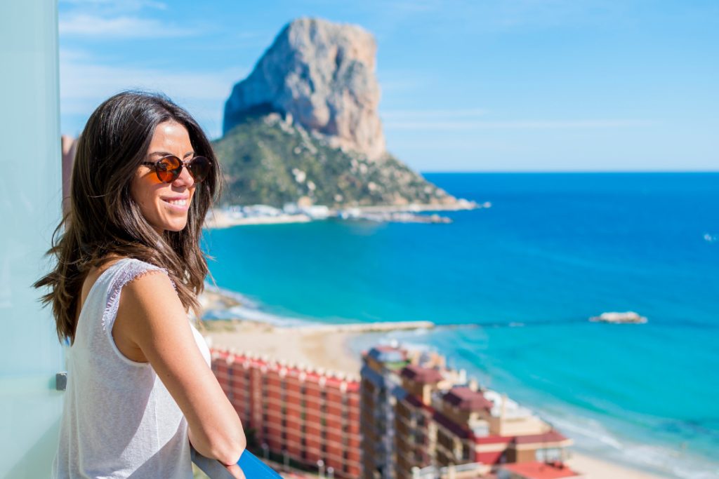 Chica mirando la playa con el fondo del Peñón de Ifach en Calpe, Costa Blanca, Alicante