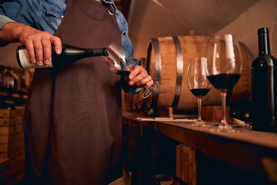 Conoce el mejor sabor de la Costa Blanca, sommelier sirviendo un vino tiento en bodega de España